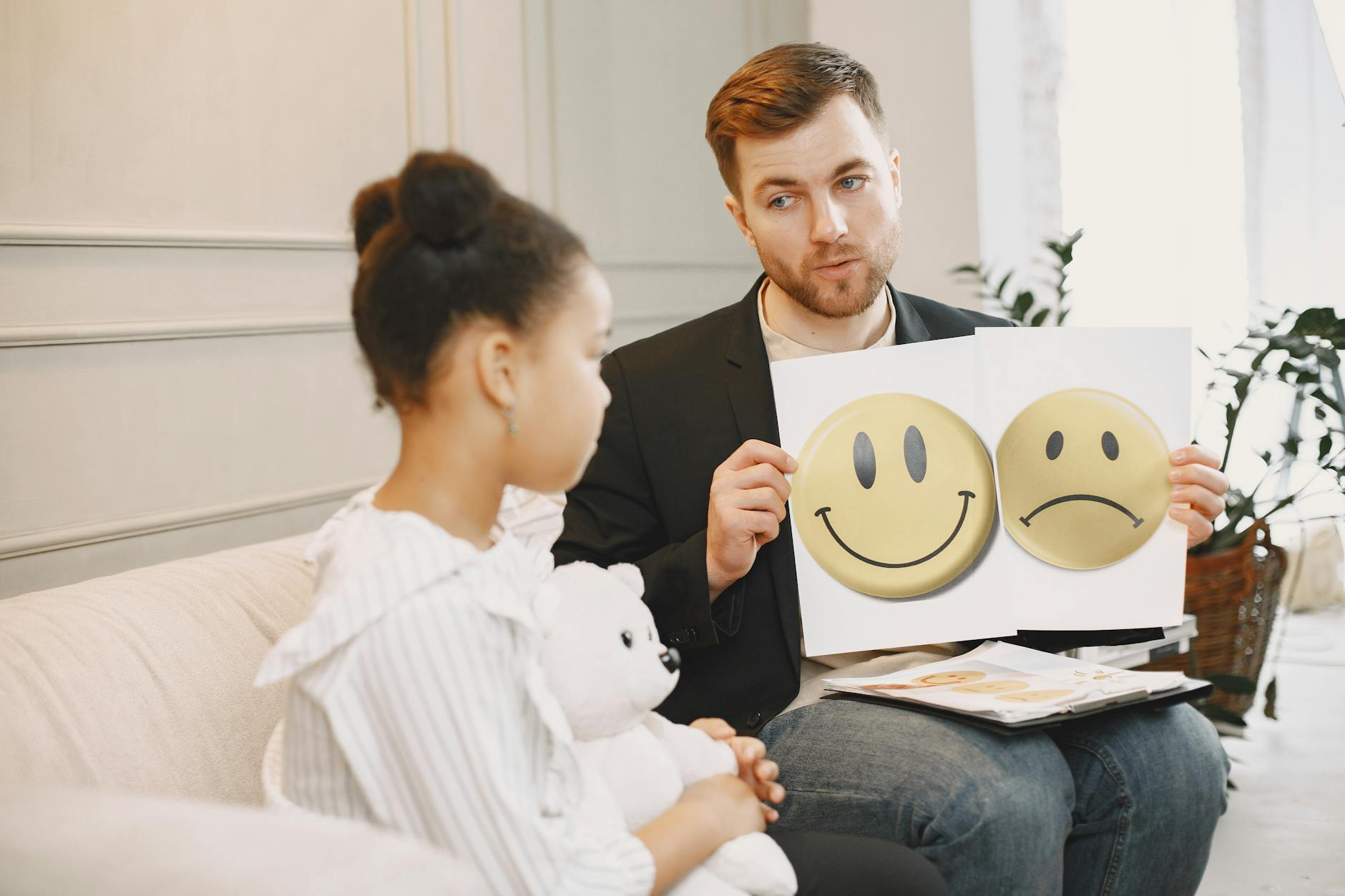 Ein Kleinkind sitzt auf dem Schoß eines Elternteils und schaut gemeinsam in ein Bilderbuch, während der Erwachsene vorliest – ein Moment der sprachlichen Förderung und Bindung.