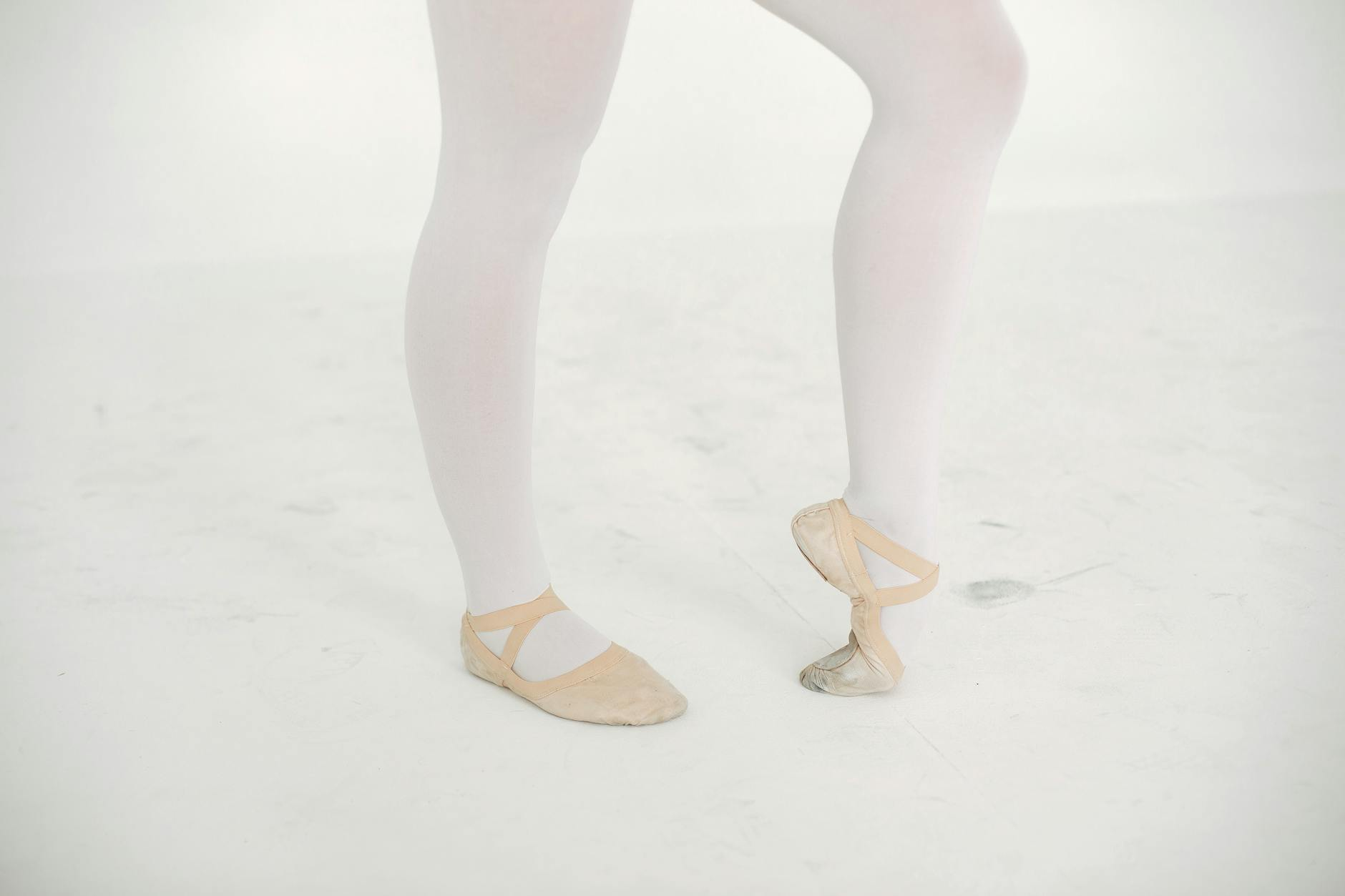 Eine Frau mit warmen Socken und einer Tasse Tee sitzt entspannt auf einem Sofa und hält ihre Füße auf einem Kissen, während draußen winterliches Wetter zu sehen ist.