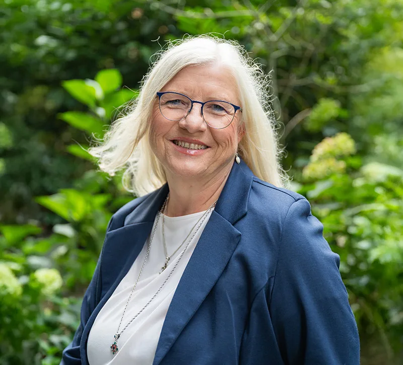 Ulrike smiling outdoors with lush green background, embodying natural vitality, growth, and the inner lightness the article promotes.