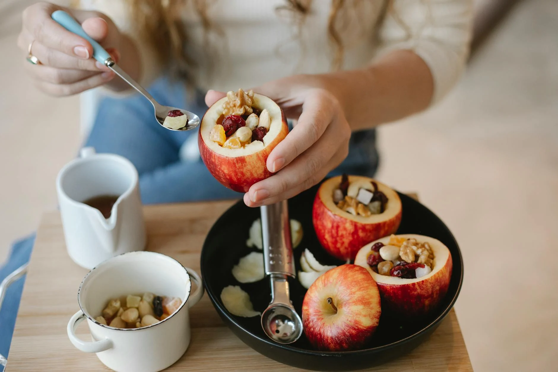 Ein frisches, gesundes Dessert in einem Glas, bestehend aus Schichten von Avocado-Mousse, Beeren und Hafercrumble, natürlich beleuchtet auf einem Holztisch mit einfachen Küchenutensilien im Hintergrund.