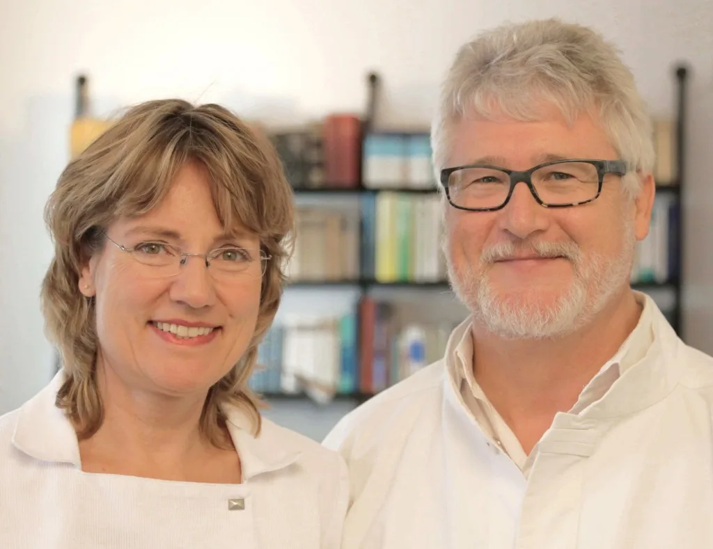 Dr. Reuter and colleague in professional setting with bookshelves, showing collaborative, evidence-based medical approach.